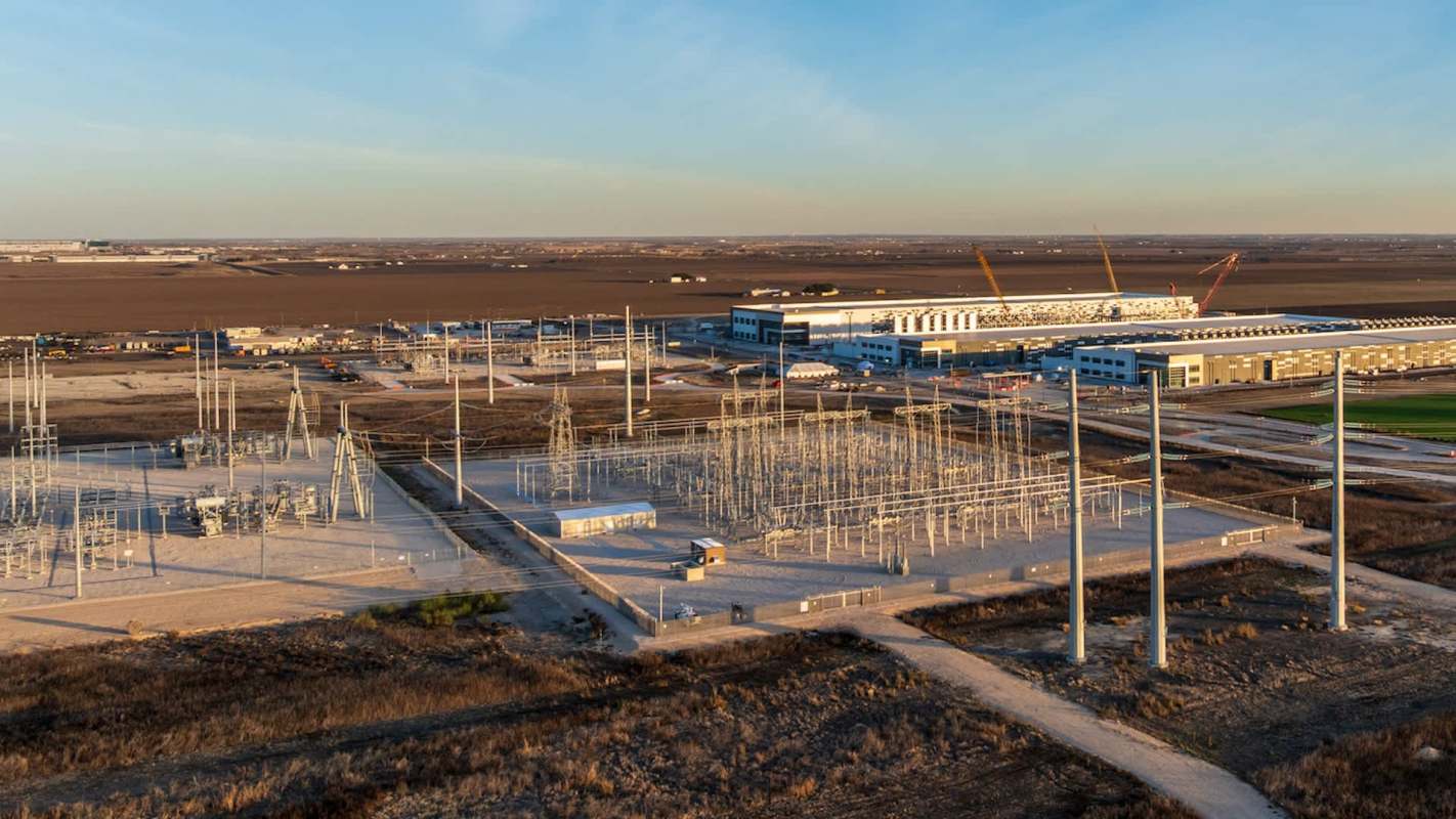 An industrial power station with electrical infrastructure and buildings under a clear sky.