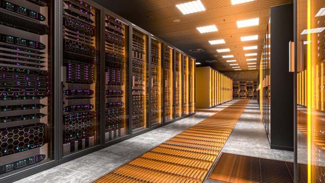 A data center aisle lined with server racks and illuminated with orange lighting.