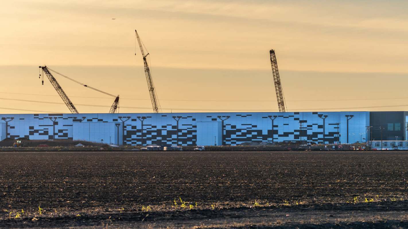 A construction site with cranes beside a large building.