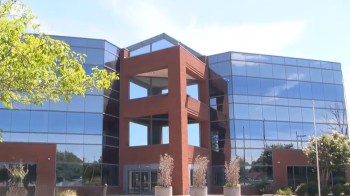 A modern building with a glass facade and a brick structure featuring large windows and decorative planters.