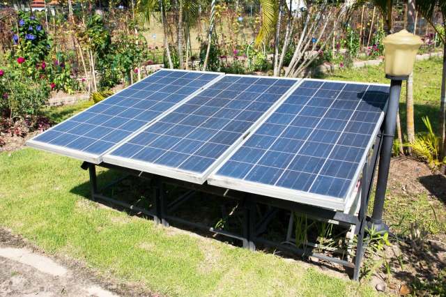 Three solar panels in a backyard.