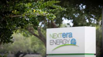 A sign for NextEra Energy surrounded by greenery.