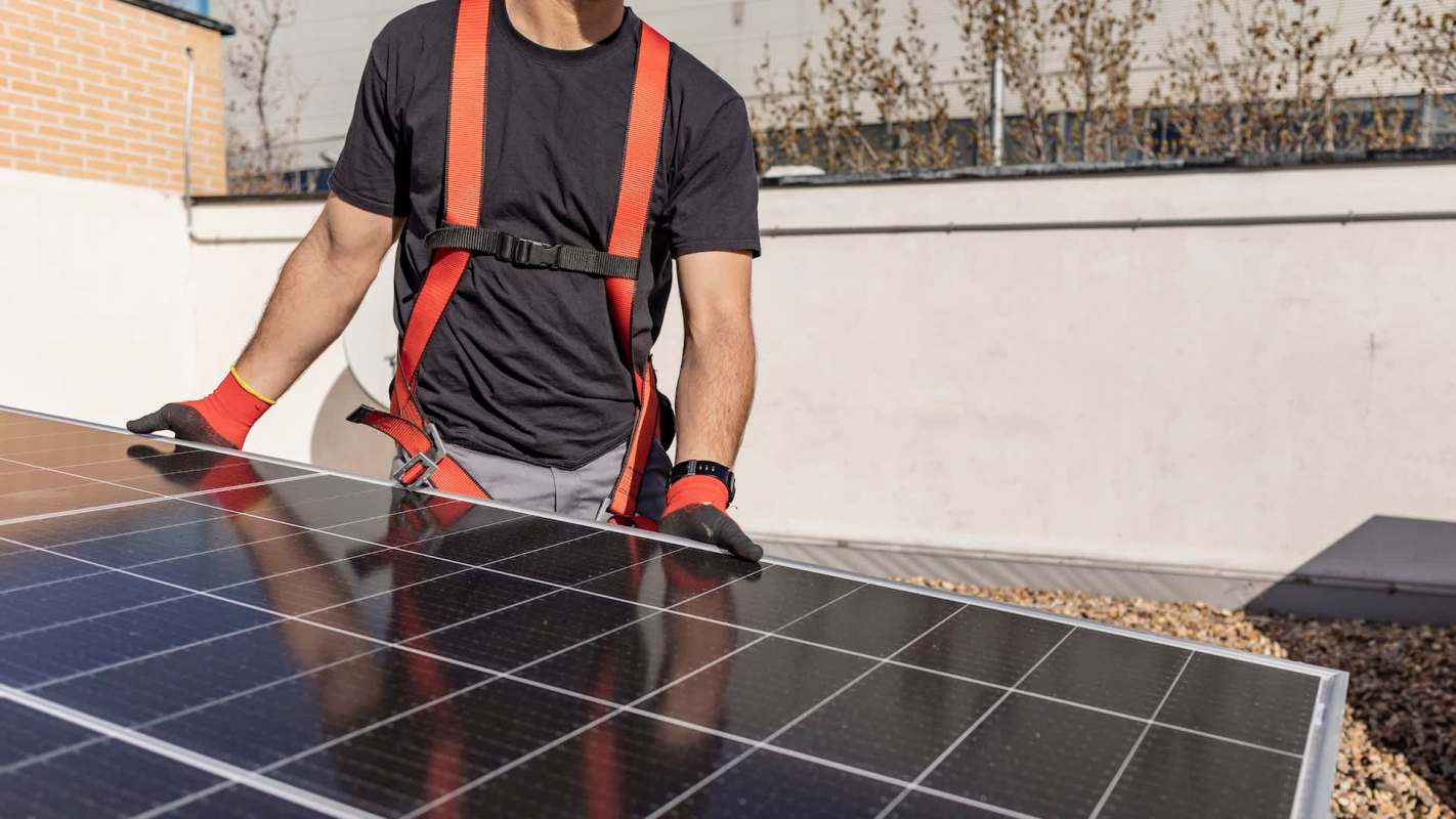 A person in a harness secures a solar panel on a rooftop.