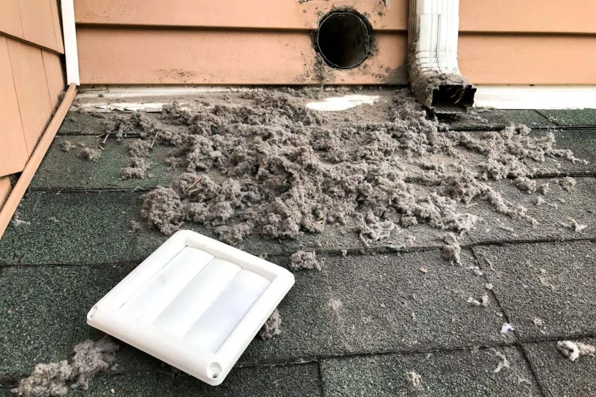 A roof area covered in lint and debris near a vent and a detached vent cover.