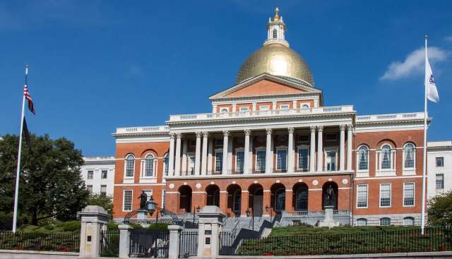 The Massachusetts State House with a gold dome and surrounding gardens.