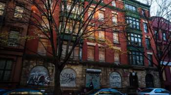 An urban apartment building with boarded-up windows.