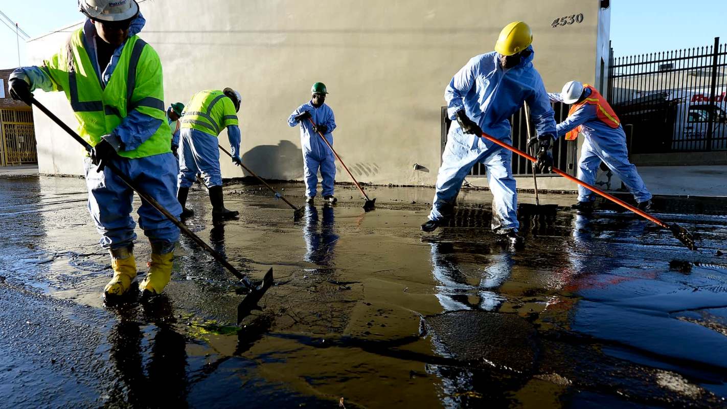Workers in protective gear cleaning up an oil spill.