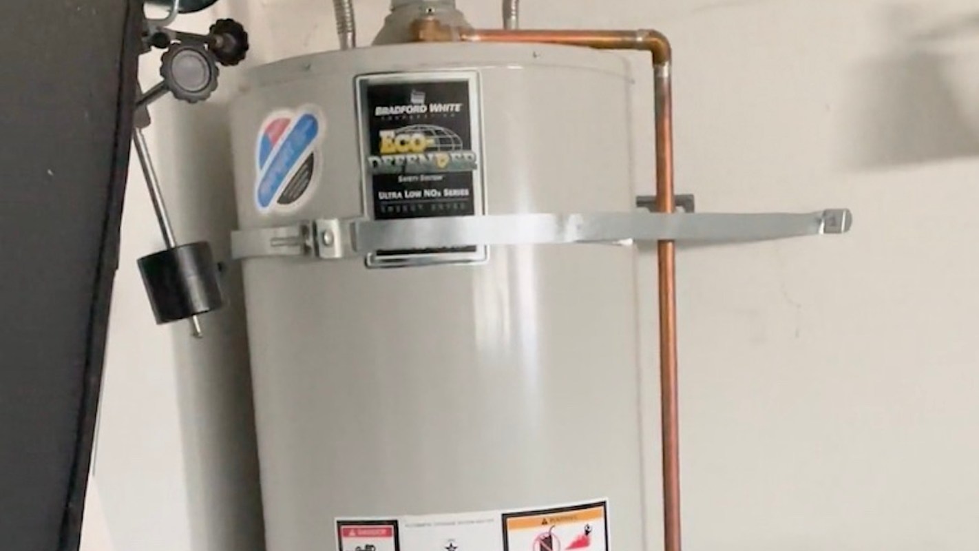 A water heater installed on a wall with copper piping and safety labels.