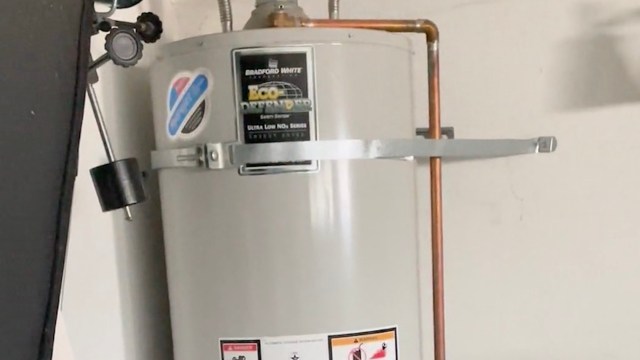 A water heater installed on a wall with copper piping and safety labels.