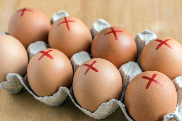 A carton of eggs with red X markings on each one.