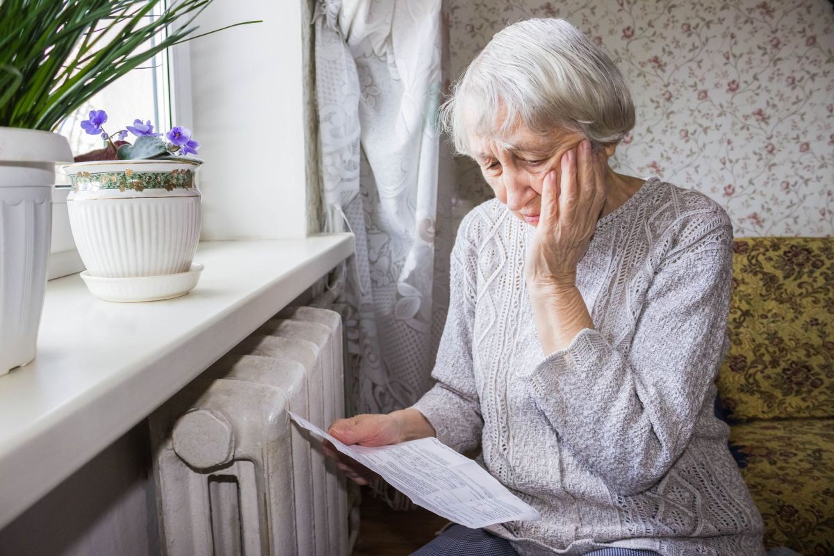 An elderly woman looking at a bill.