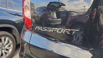 The rear of a black SUV displaying the "PASSPORT" emblem with reflections of other vehicles in the background.