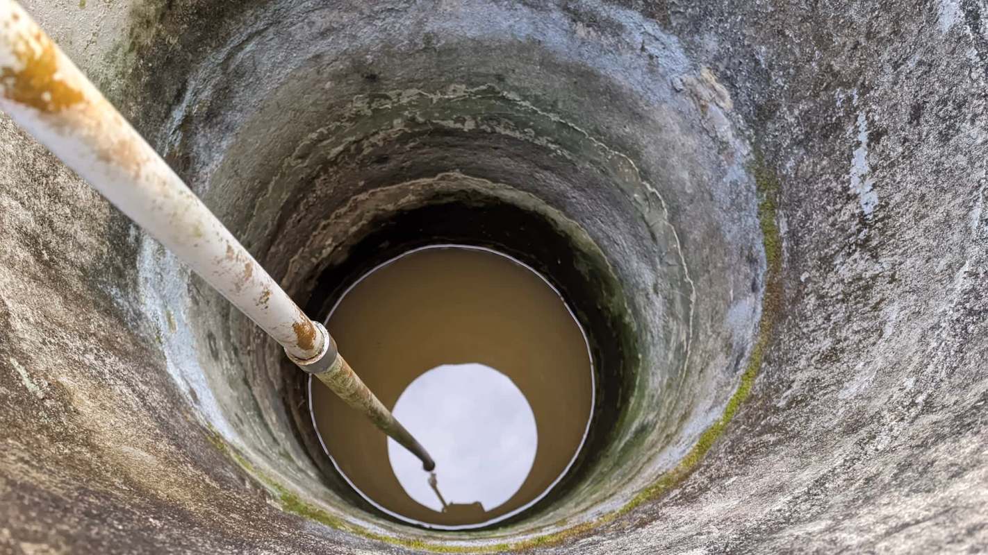 A view of a well with a pipe extending into muddy water.