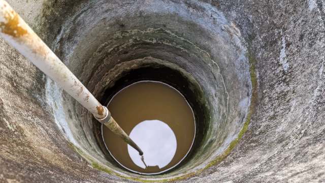 A view of a well with a pipe extending into muddy water.