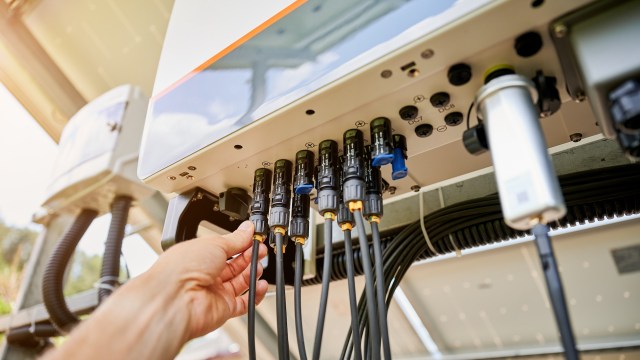 A person connecting cables to an inverter.