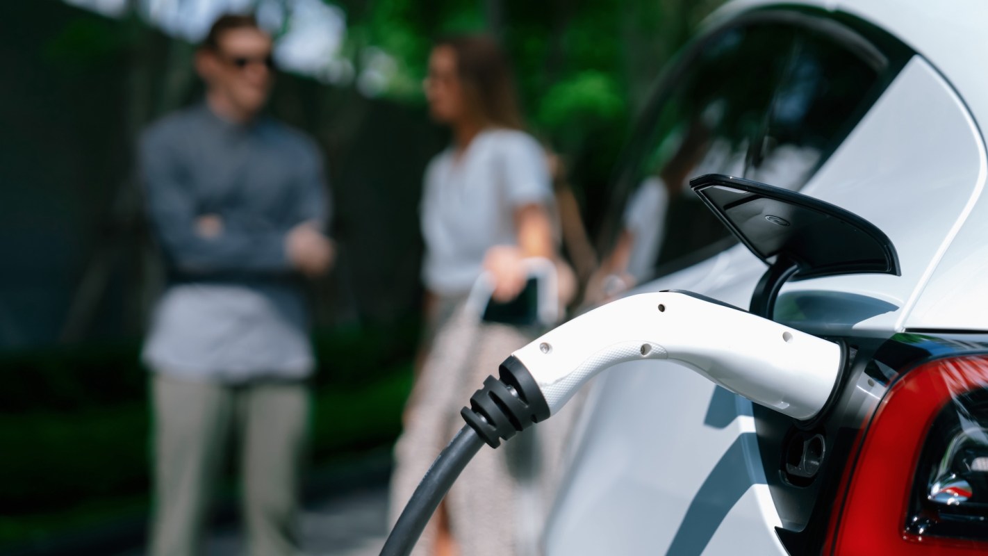 An electric vehicle charging station with two people in the background.