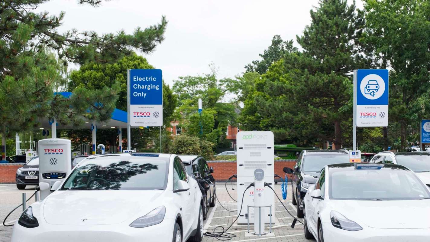 Electric vehicles charging in a supermarket parking lot.