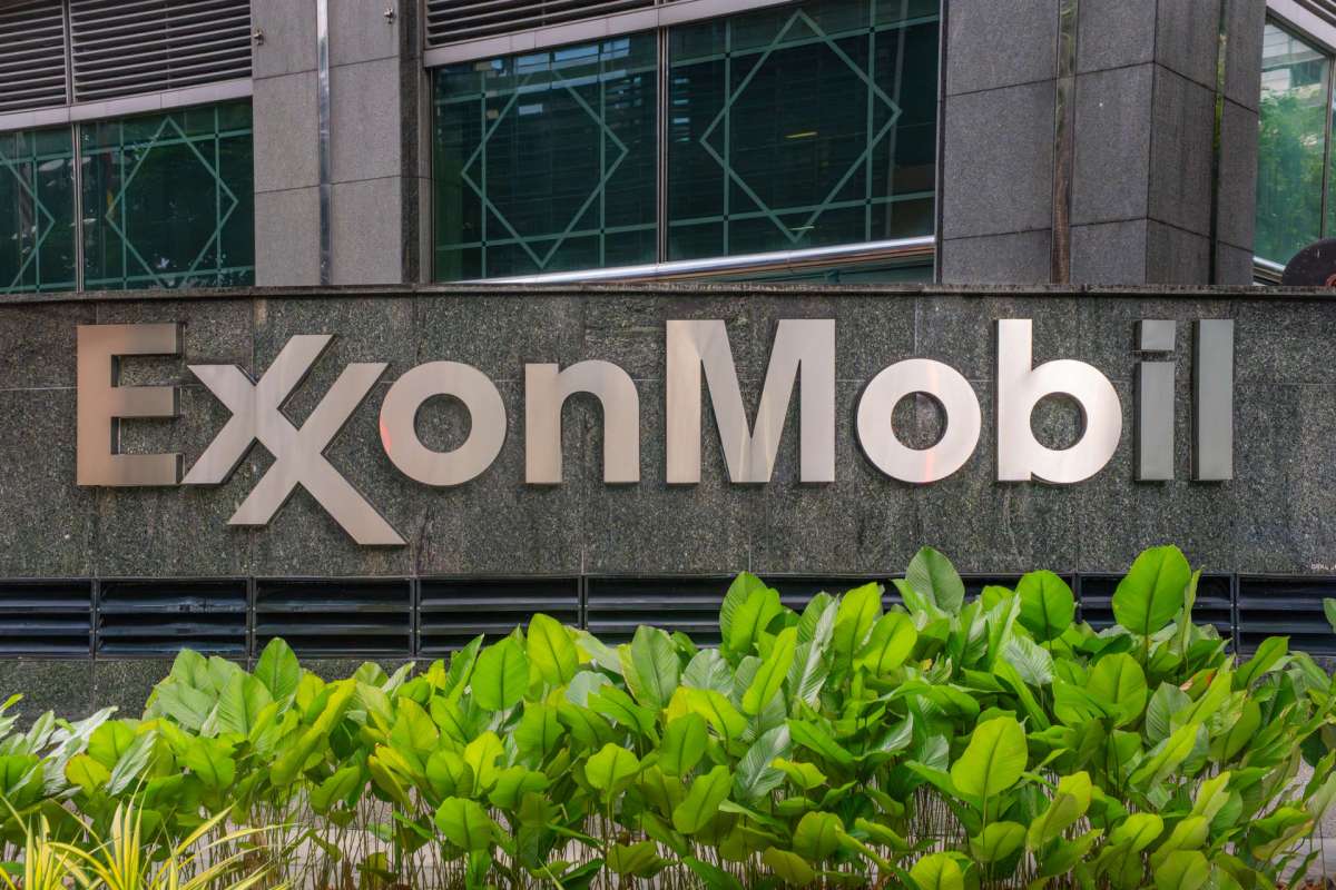 ExxonMobil sign displayed on a stone wall with green plants at the base.