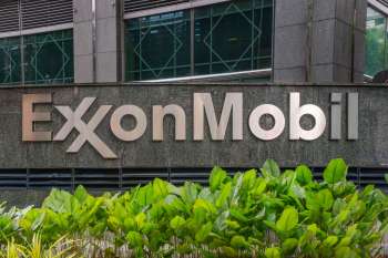 ExxonMobil sign displayed on a stone wall with green plants at the base.