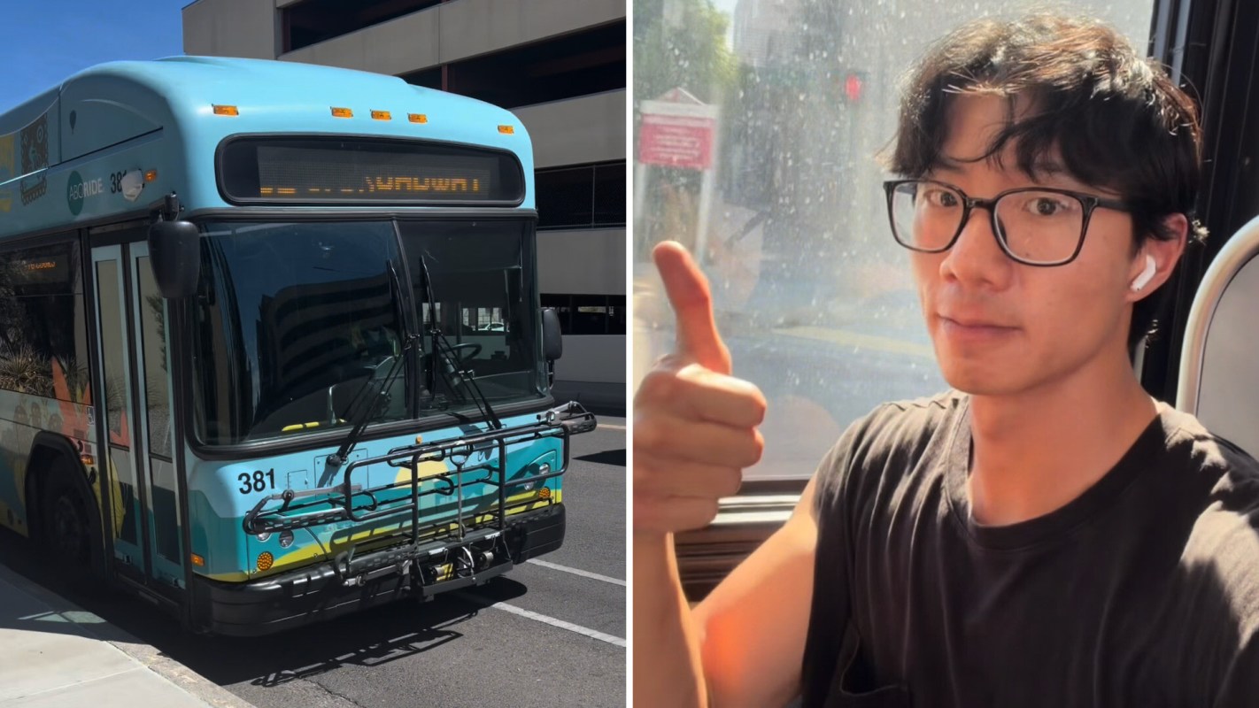 A bus parked on the street next to a person giving a thumbs up while sitting on a vehicle.