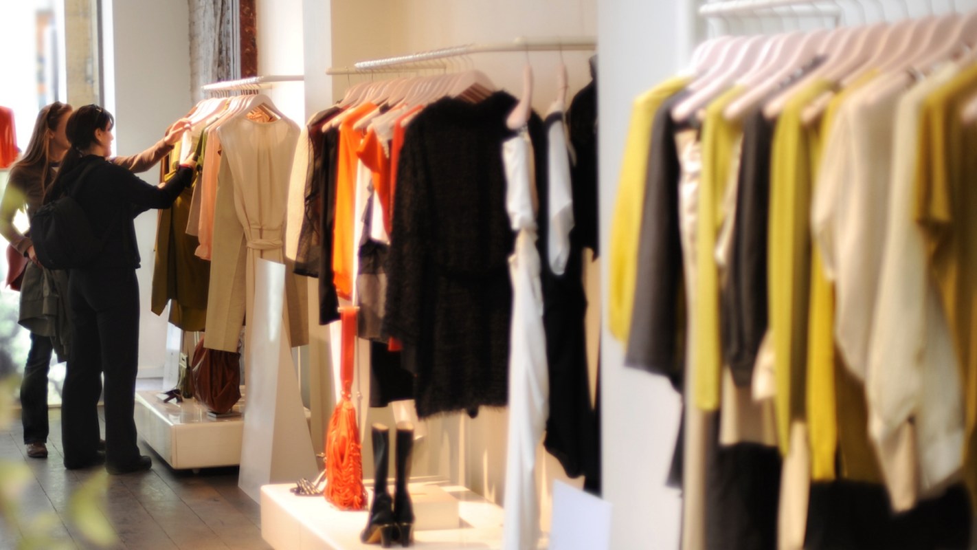 A woman browsing clothing on display racks in a retail store.