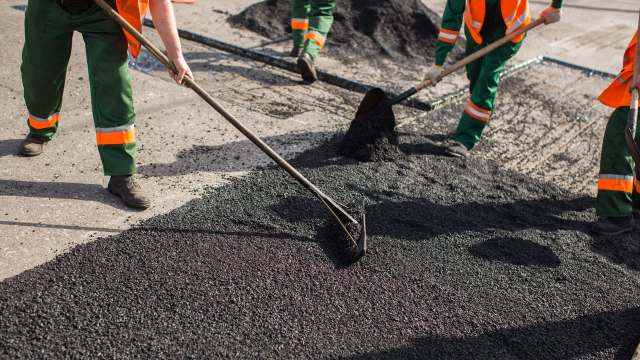 Workers laying asphalt.