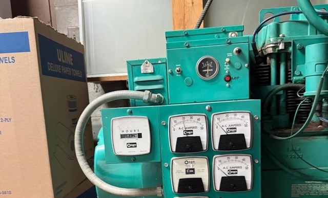 A turquoise control panel with meters and gauges for monitoring electrical output.