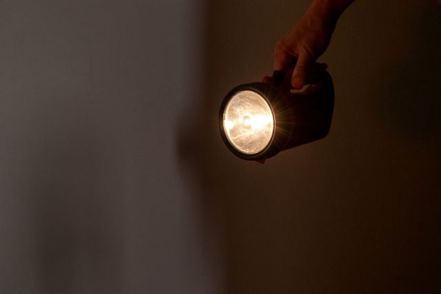 A person holding a flashlight in a dark room.