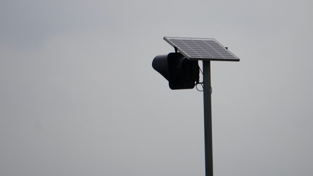 A Flock safety camera mounted on a pole against a cloudy sky.