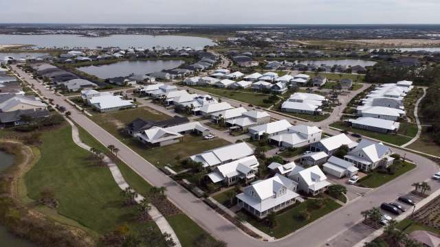 Aerial view of a suburban area with houses, roads, and nearby bodies of water.