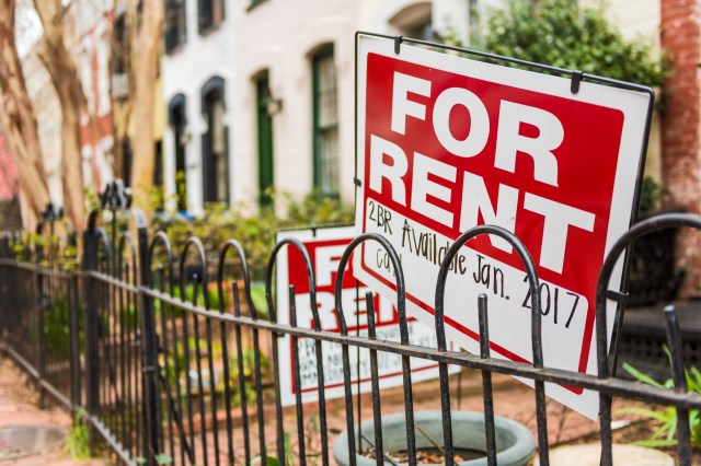 Several "For Rent" signs are displayed near a fence in a residential area.
