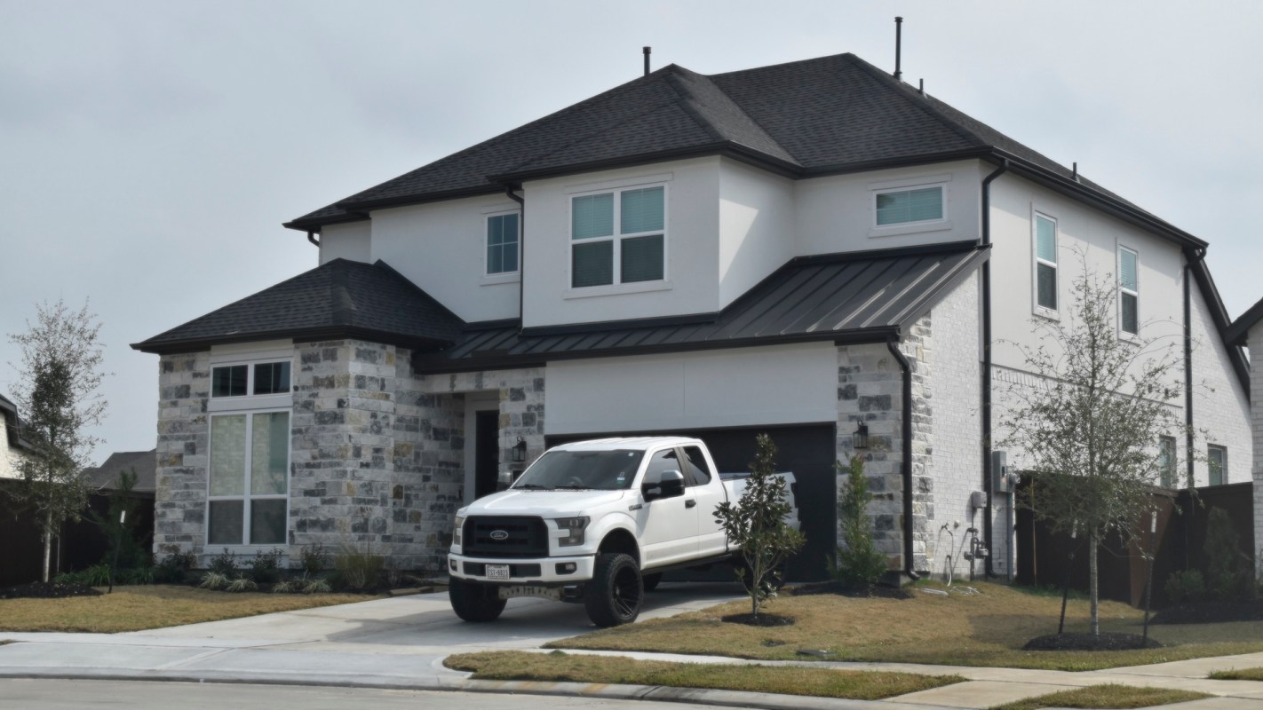 A modern two-story house with a stone facade and a white pickup truck parked in the driveway.
