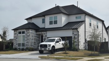 A modern two-story house with a stone facade and a white pickup truck parked in the driveway.