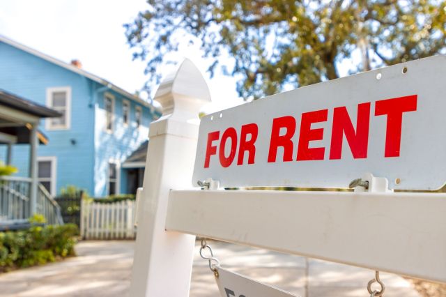 A "for rent" sign in front of a house.