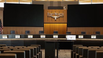 A conference room with a long table, chairs, and a large screen displaying "Fort Worth."