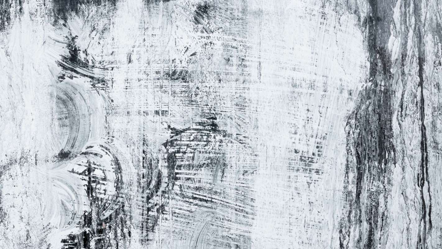An abstract texture of black and white brush strokes on a surface.