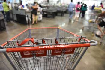 A shopping cart with "COSTCO WHOLESALE" label in a busy retail store.