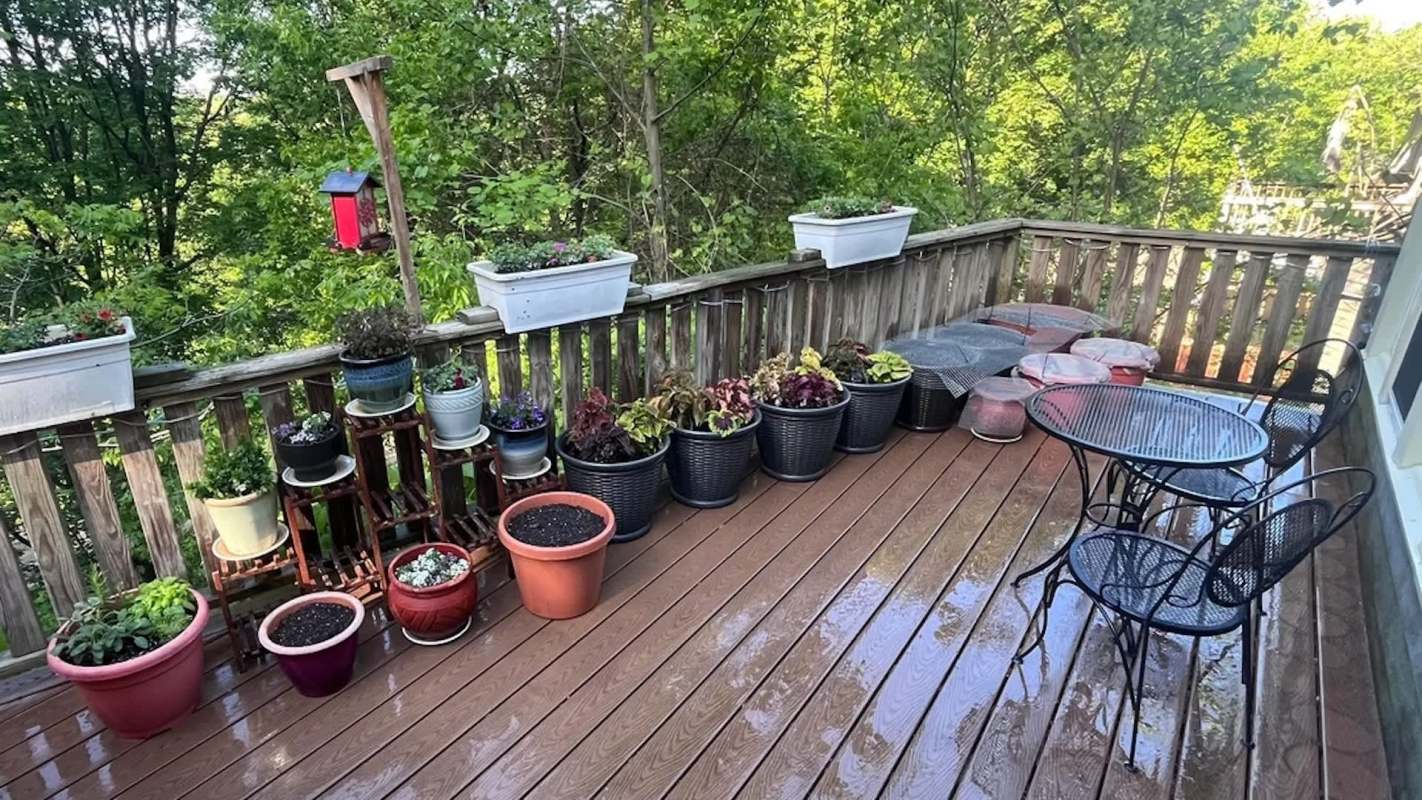 A deck with various potted plants and a small dining set.