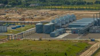 An industrial site with storage silos, machinery, and ongoing construction in the surrounding area.