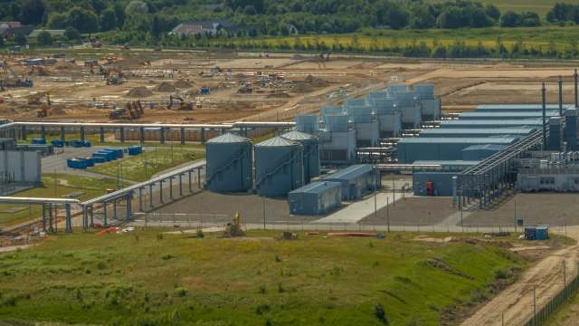 An industrial site with storage silos, machinery, and ongoing construction in the surrounding area.