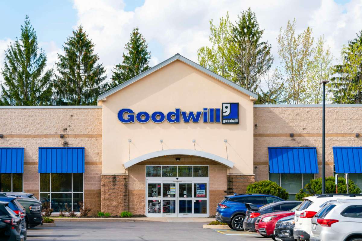 A Goodwill store building with blue awnings and parked cars in front.