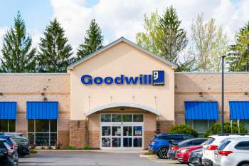 A Goodwill store building with blue awnings and parked cars in front.