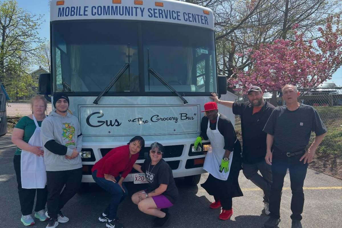 People standing in front of the "Gus the Grocery Bus."