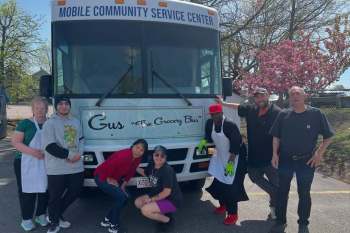 People standing in front of the "Gus the Grocery Bus."