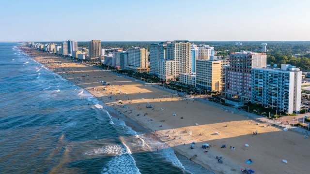 A beachside view featuring hotels, sandy shores, and people enjoying the ocean.