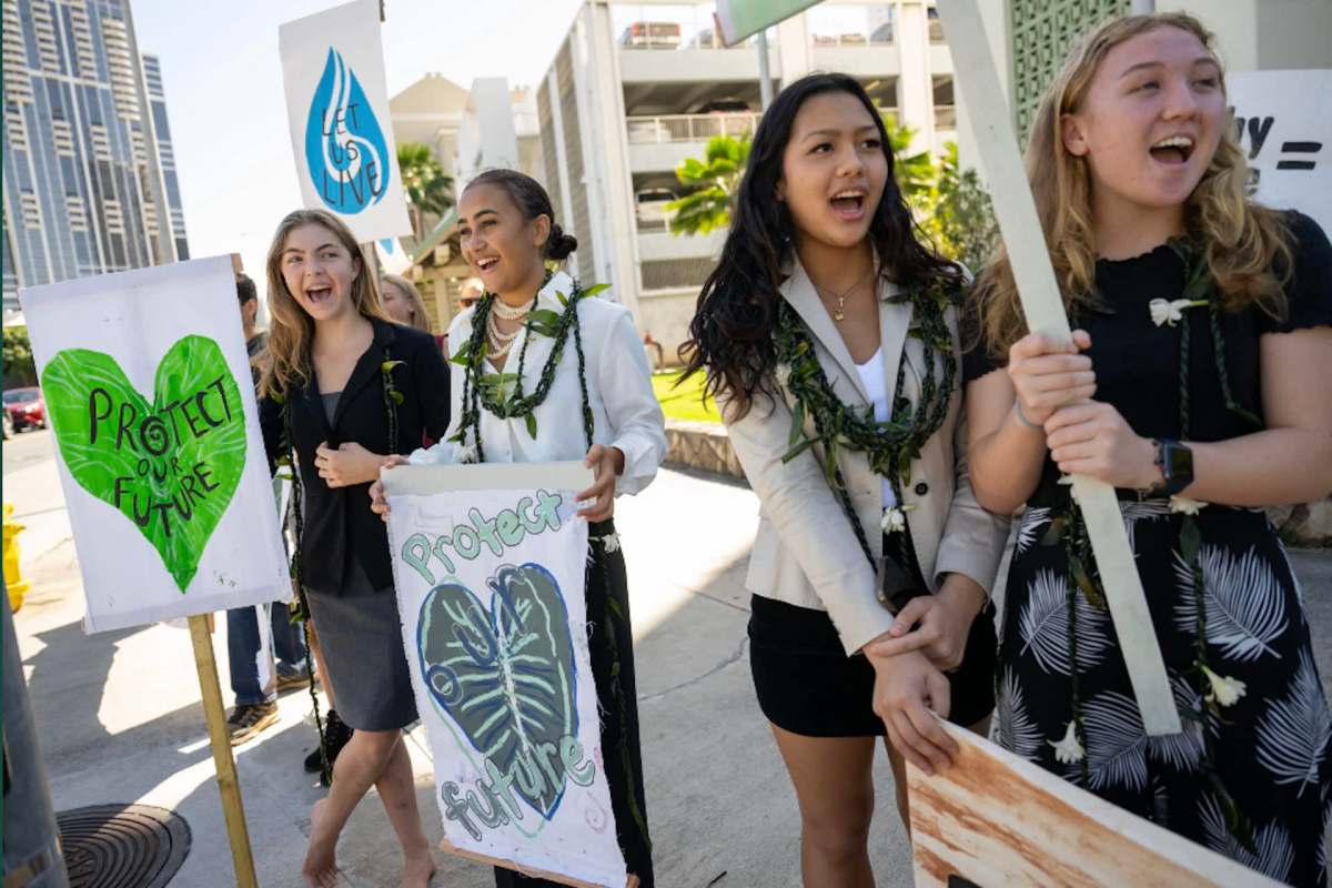 A group of young people hold signs advocating for environmental protection.