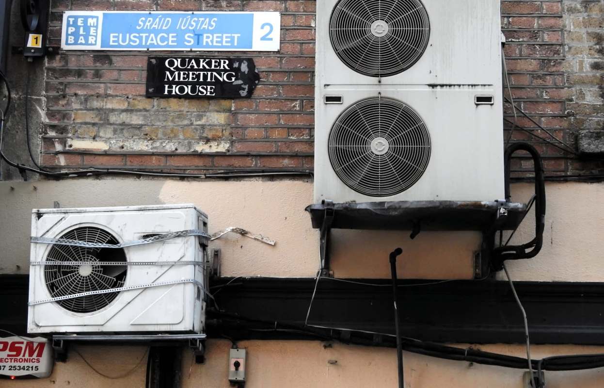 A street sign for Eustace Street above two air conditioning units next to a sign for the Quaker Meeting House in Dublin.