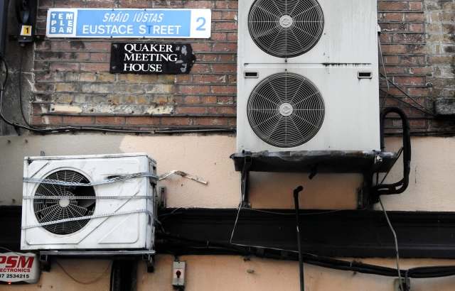 A street sign for Eustace Street above two air conditioning units next to a sign for the Quaker Meeting House in Dublin.