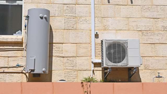 A water heater and an heat pump mounted on an exterior wall.