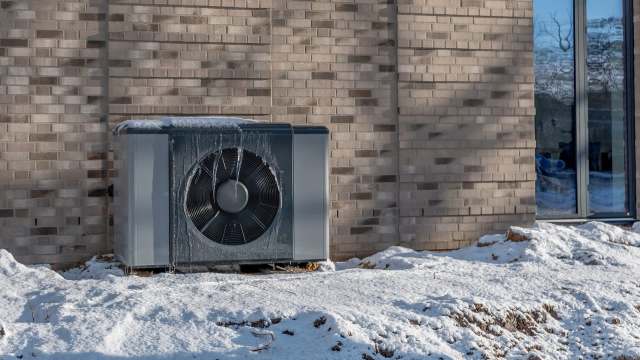 An outdoor heat pump surrounded by snow.